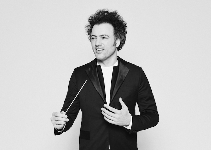 Black and white photo of Music Director Eric Jacobsen, in a tuxedo holding his baton.