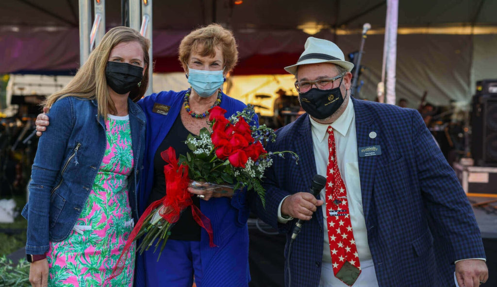 Photo of Melody Lynch, Dr. Mary Palmer, Paul Helfrich (left to right) outside at Festival Park in front of Orchestra.